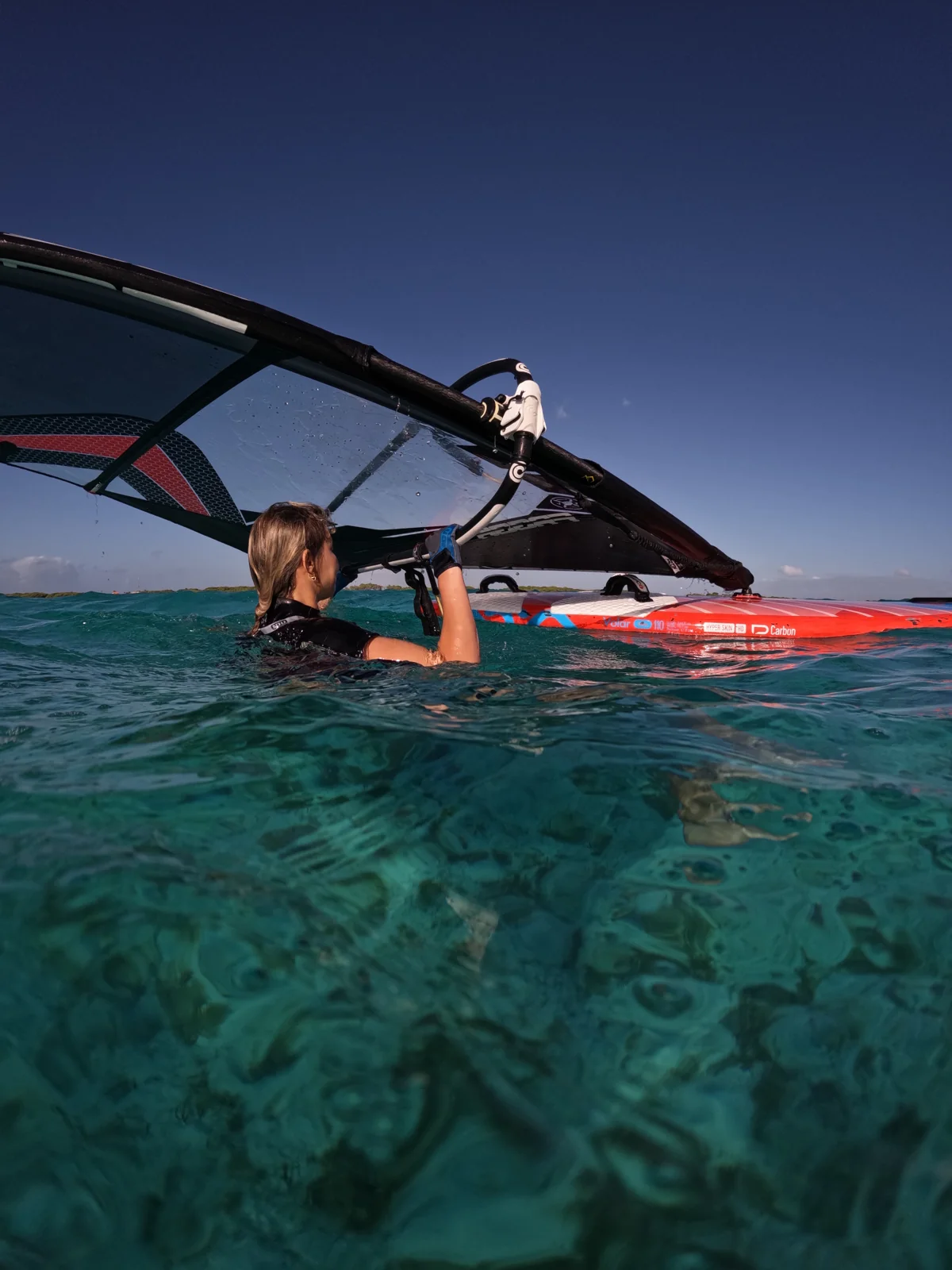 Relaxing beside windsurf equipment in clear water